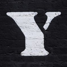 the letter y is painted white on a black brick wall and it appears to have been stenciled