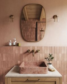 a bathroom sink sitting under a round mirror next to a wooden cabinet and counter top