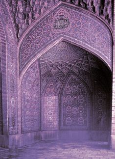 the entrance to an ornate building with purple hued lighting and intricate carvings on it