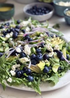 a salad with blueberries, cucumbers and onions on a white platter