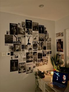 a laptop computer sitting on top of a desk next to a wall covered in pictures