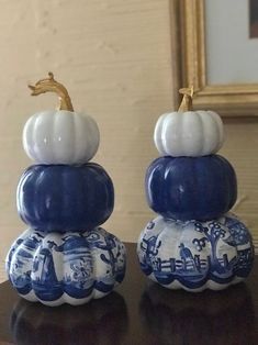 two blue and white ceramic pumpkins sitting on top of a table next to a mirror