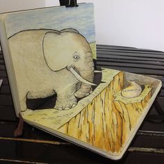 an elephant standing on top of a wooden table next to a drawing of a ball