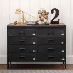 a black dresser with numbers on it and a lamp in the corner next to it