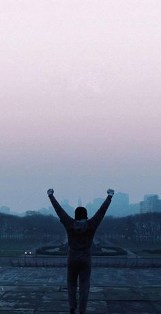 a person standing in the middle of a park with their hands up and arms wide open