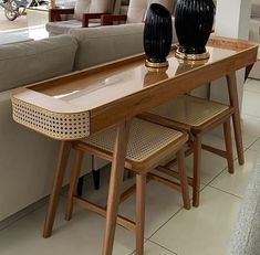 two black vases sitting on top of a wooden table in front of a couch