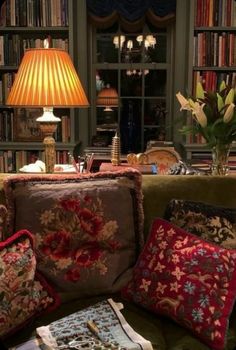 a living room filled with lots of furniture and books on top of a green couch