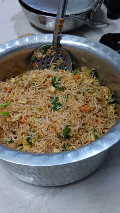 a silver bowl filled with rice and vegetables