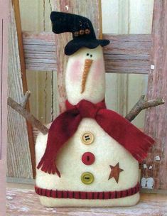 a snowman with a black hat and red scarf sitting on top of a wooden fence