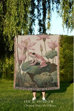 a woman is standing in the grass with a blanket on her back that has pink flowers and green leaves