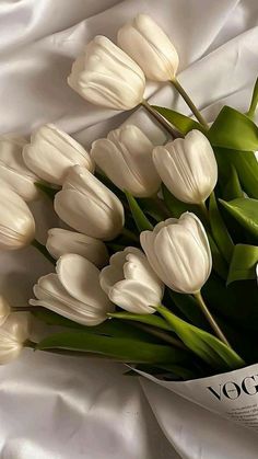 a bouquet of white tulips laying on top of a bed