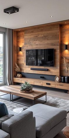 a living room with couches, tables and a television on a wooden paneled wall