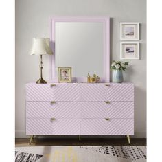 a pink dresser with a mirror and pictures on the wall next to an area rug