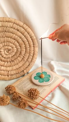 a person is holding an object on top of a book and some straws are next to it