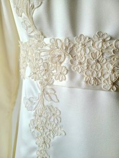 the back of a white wedding dress with flowers on it's waist and belt