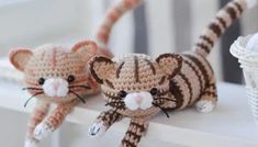 two crocheted cats sitting on top of a white shelf