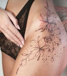 a close up of a woman's thigh with tattoos on it and flowers in the middle