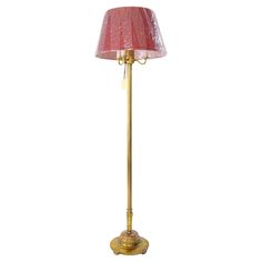 a floor lamp with a pink shade on the base and a gold colored metal pole