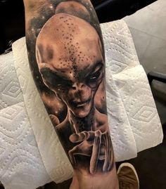 a man's arm with an alien tattoo on it