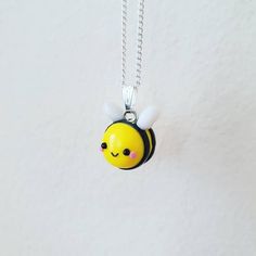 a yellow and black necklace with a bee on it's back hanging from a silver chain