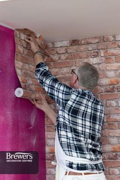 a man painting a brick wall with pink paint