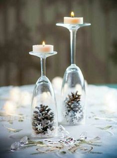 two wine glasses filled with snow and pine cones are sitting on a table next to each other