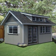 a small gray house sitting on top of a lush green field