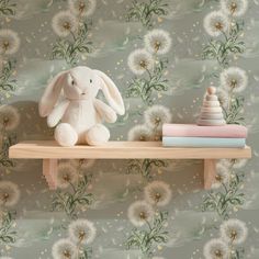 a white stuffed rabbit sitting on top of a wooden shelf next to a stack of books