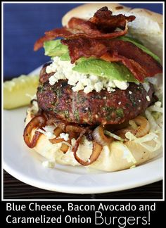 a burger with bacon, lettuce and other toppings is on a white plate