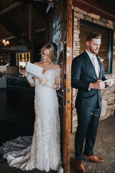 a man and woman standing next to each other in front of a door holding papers