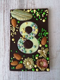 a chocolate birthday cake decorated with nuts, leaves and the number eight on it's side