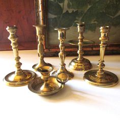 a group of brass candlesticks sitting on top of a table next to a painting