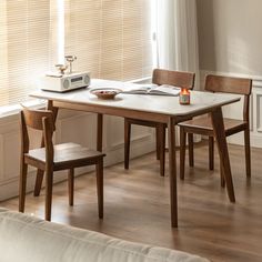 a wooden table with two chairs and a toaster on it in front of a window