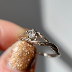 a close up of a person's hand holding a ring with a diamond on it