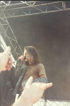 a man standing on top of a stage with his hand in front of him as he sings