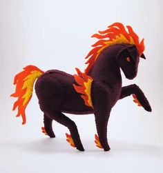 a toy horse with orange and yellow feathers on it's head, standing in front of a white background