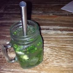 a mason jar filled with green liquid on top of a wooden table