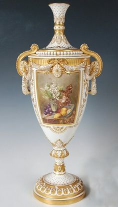 an ornately decorated vase with gold trimmings and flowers on the bottom, is shown