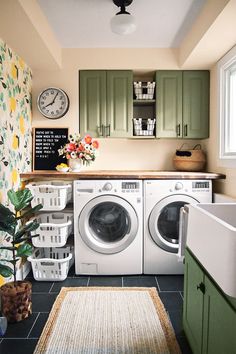 a washer and dryer in a small room with lots of green cabinetry