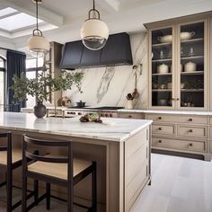 a large kitchen with marble counter tops and wooden chairs in front of an oven hood