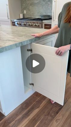 a woman is opening the cabinet door to reveal her new kitchen countertop and cabinets