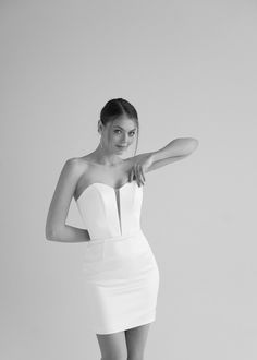 a black and white photo of a woman in a short dress posing for the camera