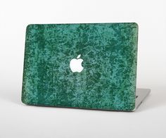 an apple logo on the back of a green macbook pro laptop computer skin that has been scratched