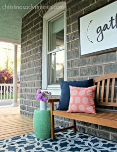 a wooden bench sitting on top of a porch next to a blue and white rug