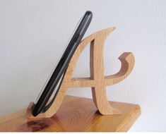 a wooden letter and pen holder with a cell phone in it's holder on top of a table