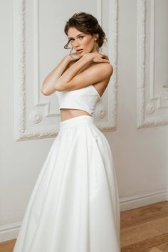 a woman in a white dress posing for the camera with her hands on her hips