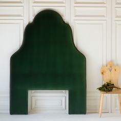 a green headboard sitting on top of a wooden chair next to a white wall