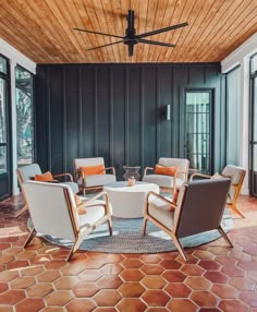 a living room with chairs and a round table in the center surrounded by wood paneled walls