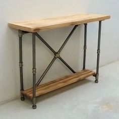 a wooden table with metal legs and a shelf on the side against a white wall