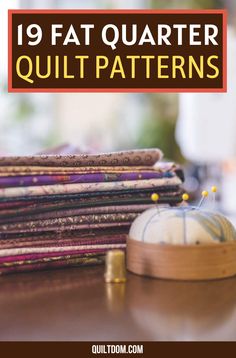 a pile of quilts sitting on top of a table next to a sewing needle